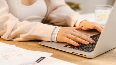 a person with manicured nails typing on laptop